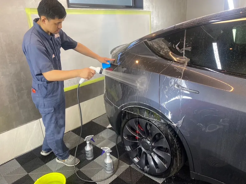 車の側面に施工液を吹きかけてフィルムをなじませる様子
